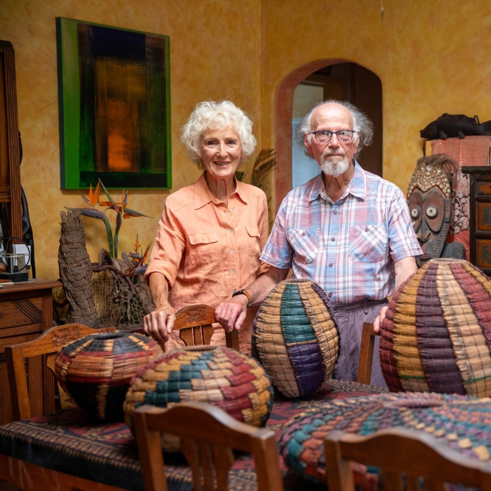 A woman and man standing next to each other with colorful baskets on a table in front of them.