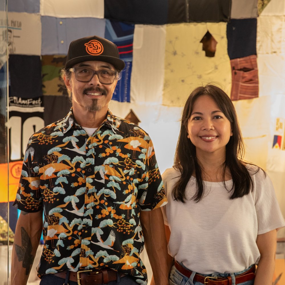 A man and woman standing in front of a display of quilts.
