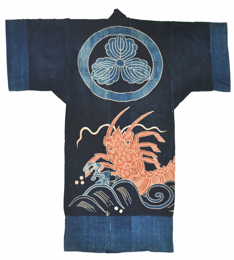 This sleeping garment (yogi) includes a lobster rising above a wave design on indigo dyed cloth. Above the lobster and wave is a circle outlining a triangular floral design.