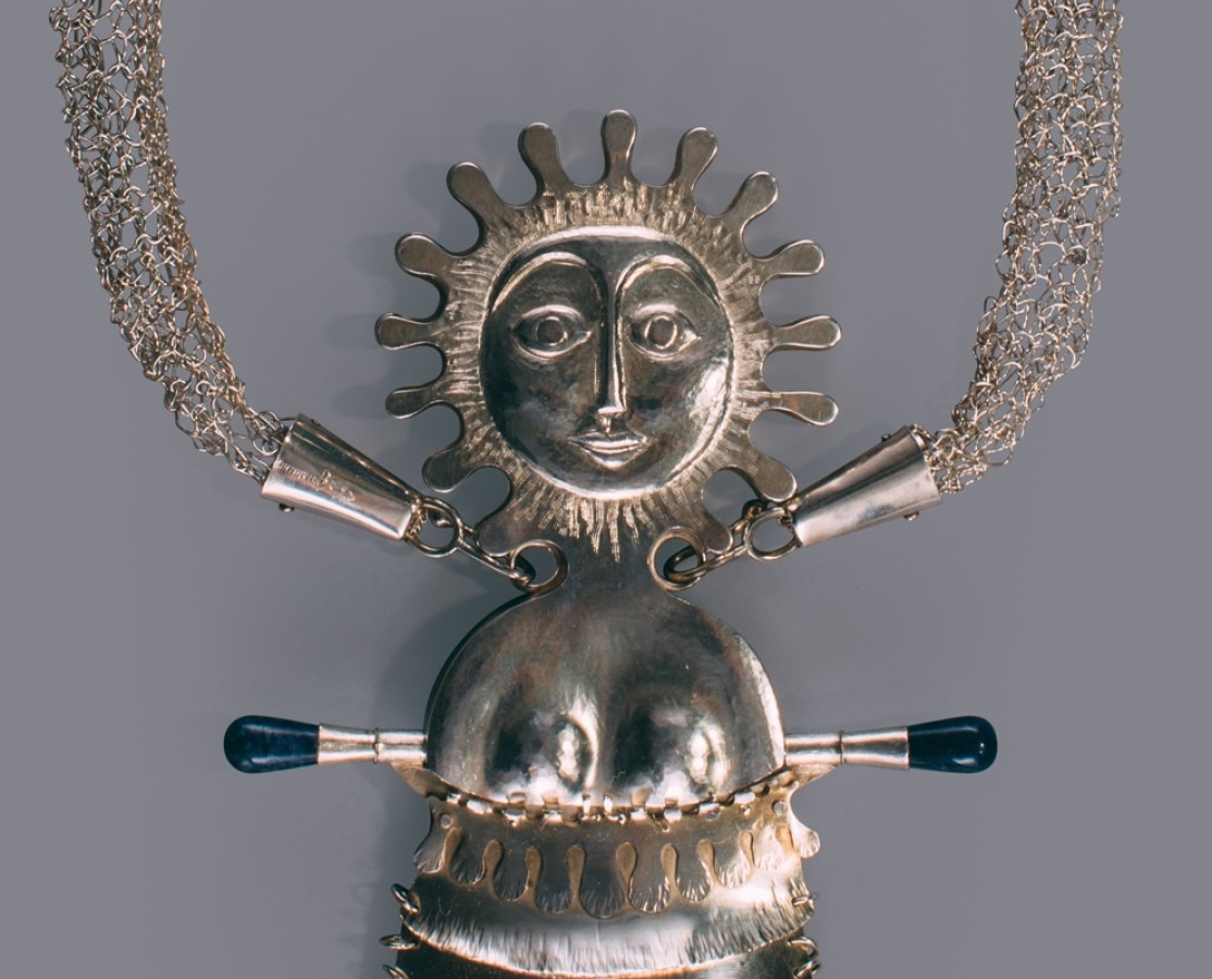 This piece is made of sterling silver and 14k gold. The main feature is a female figure.