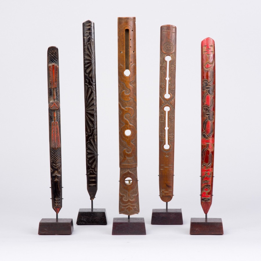 This photograph shows 5 different ainu prayer sticks. Each prayer stick has a different design and coloring, but all of them are long and slender, and about the same height.