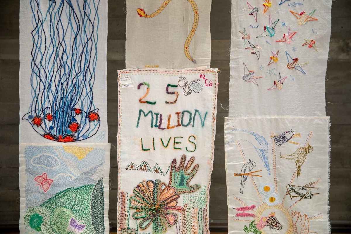 Hanging panel with embroidered words: 25 million lives.